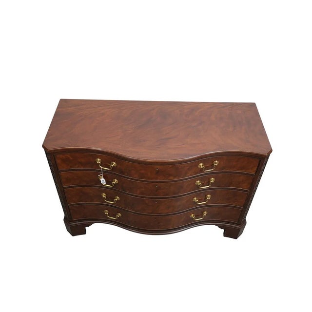 The Baker Mahogany Serpentine Front 4 Drawer Chest is a stunning antique desk with a chippendale style design. It features...