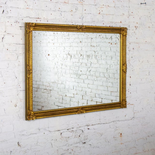 Fabulous vintage Neoclassical Rococo or French Louis style wall mirror composed of a rectangular ornate gilded wood and...