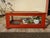 Low cabinet, designed to be placed on the floor or a table, with four legs and glass panels on five sides. The frame and...