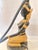 An elegant black and gold sculpture depicting a kneeling female figure in traditional Southeast Asian attire. The figure...