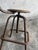 Authentic industrial workshop stool with adjustable height, wooden seat and backrest, and a patinated metal frame. The...