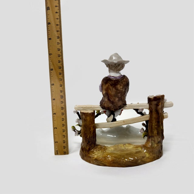 This is a charming vintage Sitzendorf porcelain spill vase featuring a young boy in 18th-century attire perched atop a...