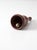 A turned vintage mid-century hand bell in warm natural wood, distinguished by its slender handle, gently flared bell, and...