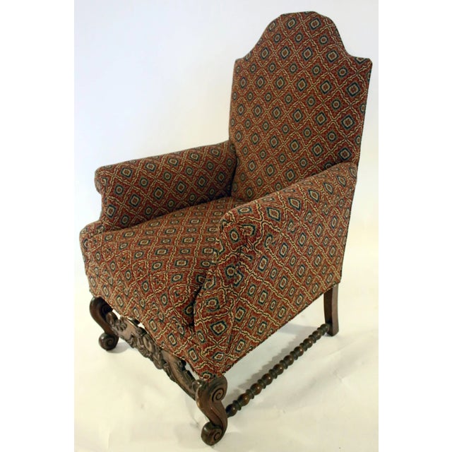 Pair of upholstered armchairs in the Jacobean revival style, circa 1890s. Features include a slight domed back and flared...