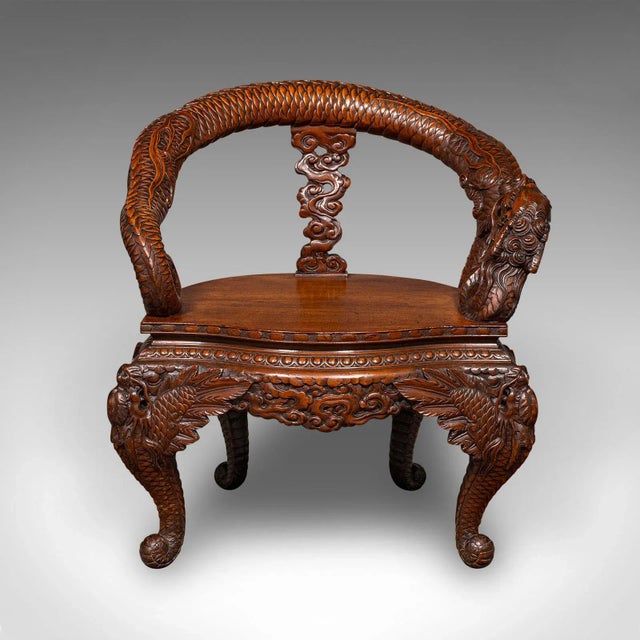 This is a vintage decorative elbow chair, an Oriental, relief carved mahogany fireside or hall seat, dating to the late...
