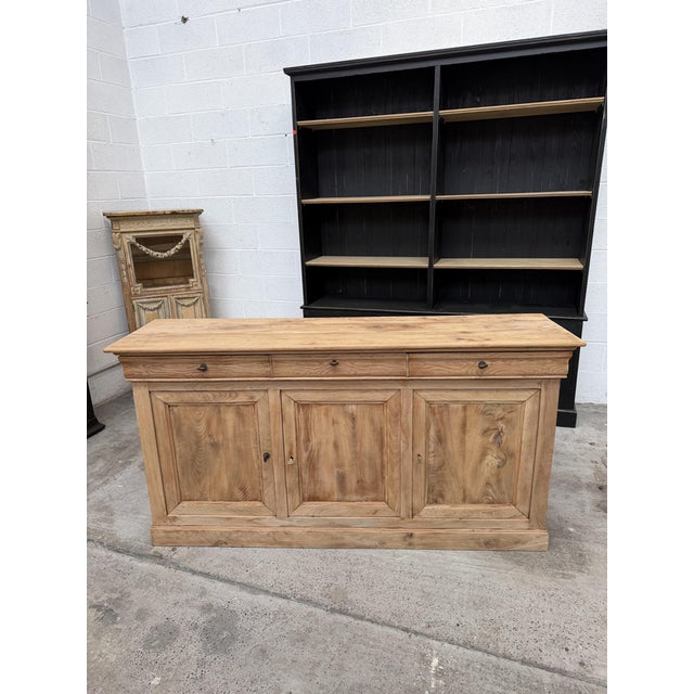 This antique sideboard made of solid elm has been fully restored. It features 3 large, functional drawers and 3 solid...