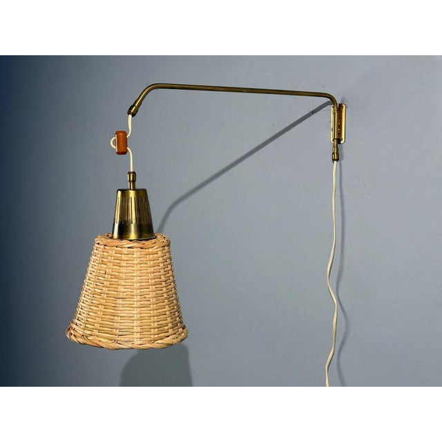 Ateljé Lyktan, Swedish Mid-Century Modern, Articulating Wall Light or Sconce, Brass, Cane, Teak, Sweden, 1970s A brass,...