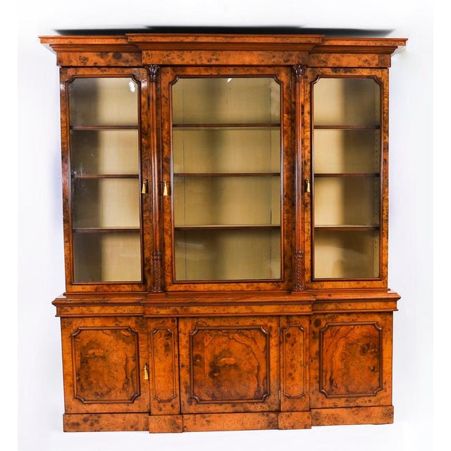A superb antique English mid-Victorian top-quality three-door breakfront bookcase, masterfully crafted in rich burr...