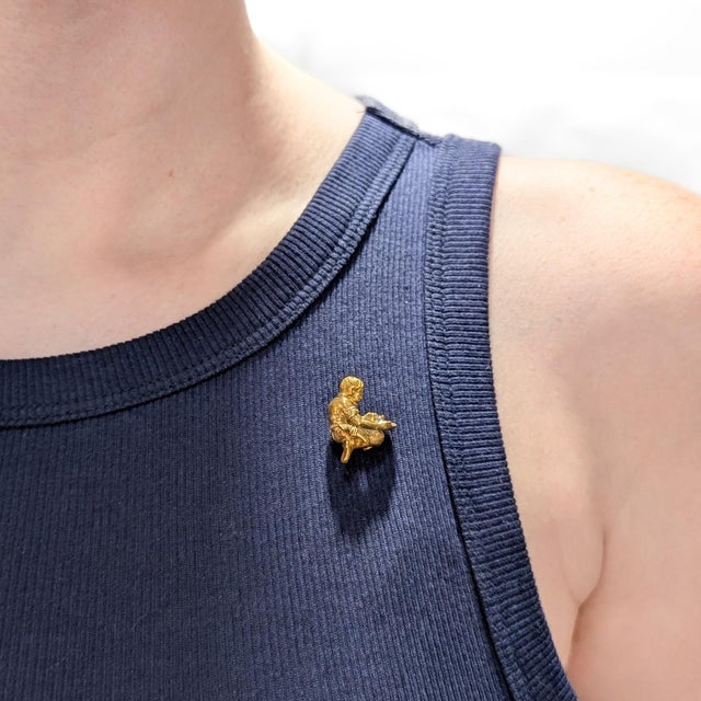 A fine antique gold and diamond stickpin. In 9 karat yellow gold. In the form of a miner panning for gold. Within the pan...