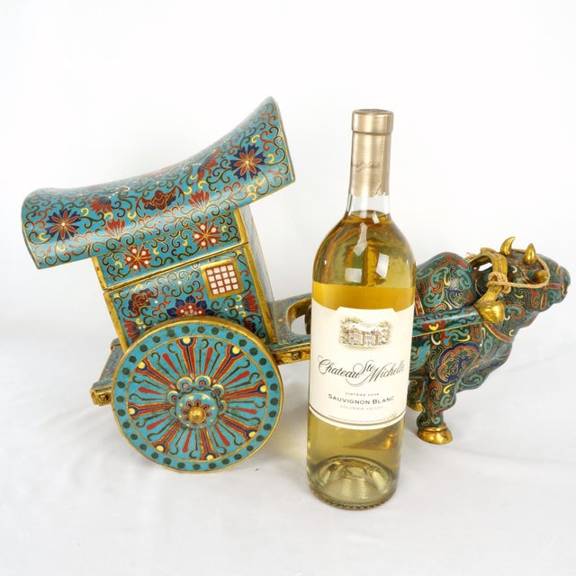 A magnificent, oversized Chinese cloisonné sculpture featuring a ceremonial ox pulling a grand covered cart. Crafted with...