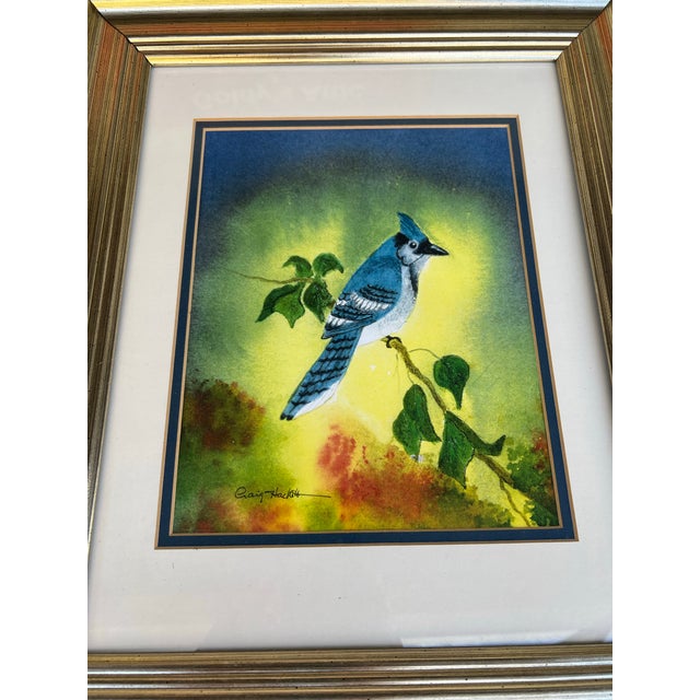 This framed art duo features two distinct nature-themed subjects: a detailed Blue Jay and a whimsical tree-filled with...