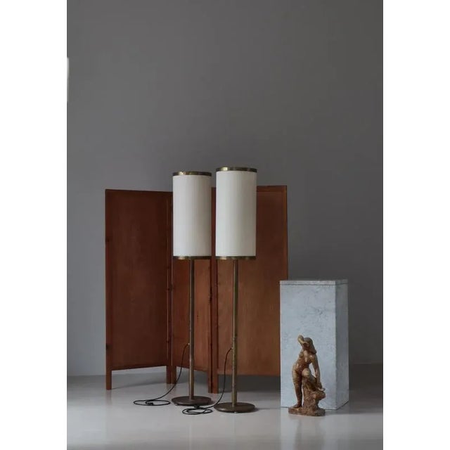 A pair of large Danish Modern floor lamps in patinated brass and acrylic shades. The lamps were made in the 1960s as part...