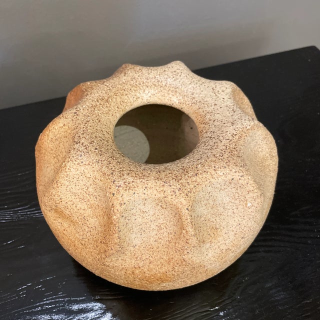 This is a low earthenware vase with wavy top design in lovely natural tones.