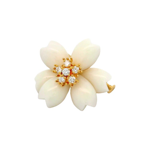 A contemporary brooch featuring a floral design, crafted with white onyx petals. The center is adorned with round white...