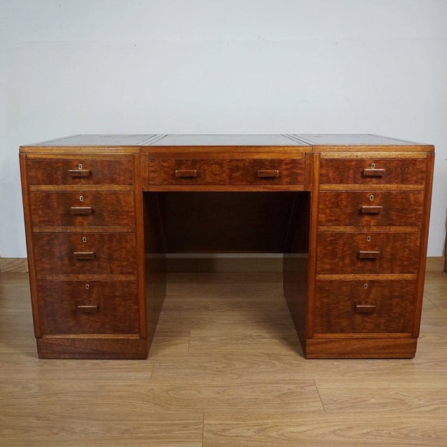 A superb art deco desk by heal's of london. Flame mahogany veneered all round with oak banding and original worn leather...
