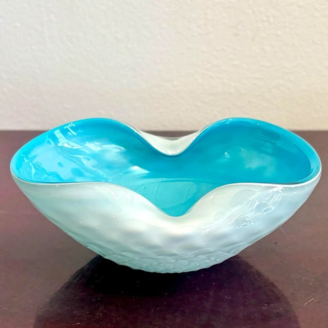This hand-blown art glass bowl is a playful study in contrast and flow. With its icy white exterior and vivid aqua...