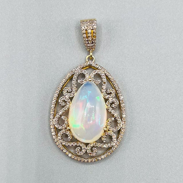 A striking vintage statement pendant centred by a large pear-shaped cabochon opal, displaying a beautiful shifting play of...
