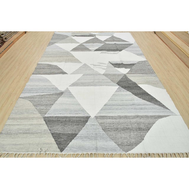A contemporary kilim rug handwoven with fine wool on a cotton foundation. This area rug features an all-over geometric...