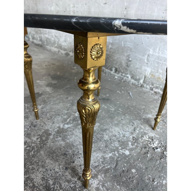 Elegant vintage coffee table with a round black marble top and ornate brass-coloured legs. The dark marble has beautiful...