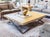 A modern geometric-infused coffee table with a poured, stained and thick square concrete top and blackened steel base with...
