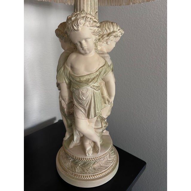 Elevate your space with classical Hollywood Regency grandeur. This striking multi-figure table lamp was manufactured by...
