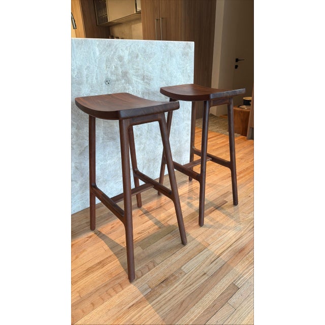 A pair of walnut solid wood barstool by Article furniture.