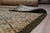 A 3' x 18' hand-knotted wool runner with an olive and gold interlocking geometric lattice inside a dark olive border....