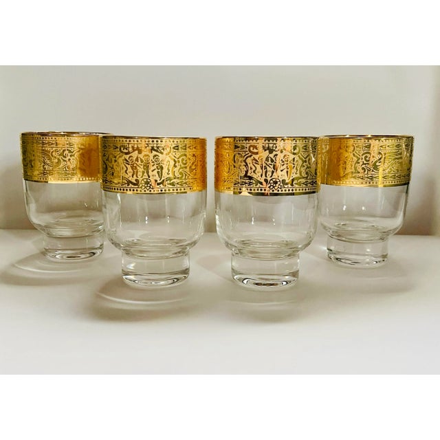 A gorgeous set of mid century bar glasses featuring an elaborate gold border of cherubs, swans and scrollwork.