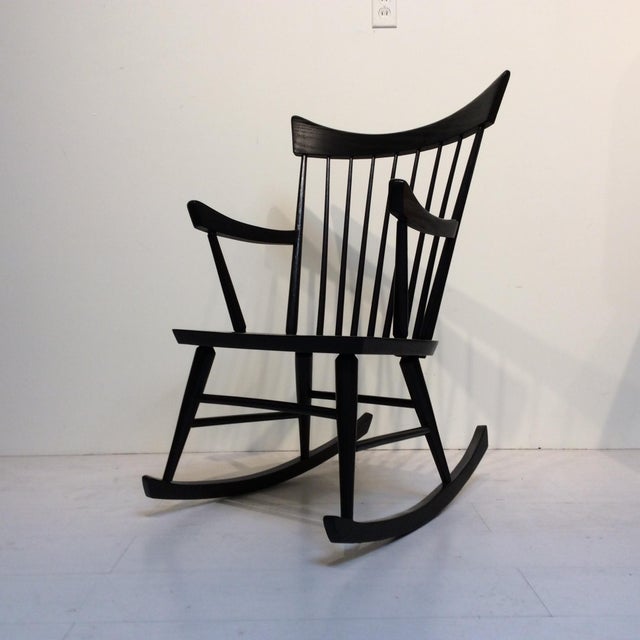 This black rocking chair is in the sleek style of Edmond Spence. The sloping shapes of this beautiful chair end in...