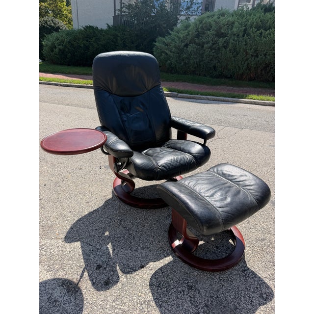 Black leather Ekornes Stressless chair & Ottoman with swivel table. The chair features a swivel base and reclining...