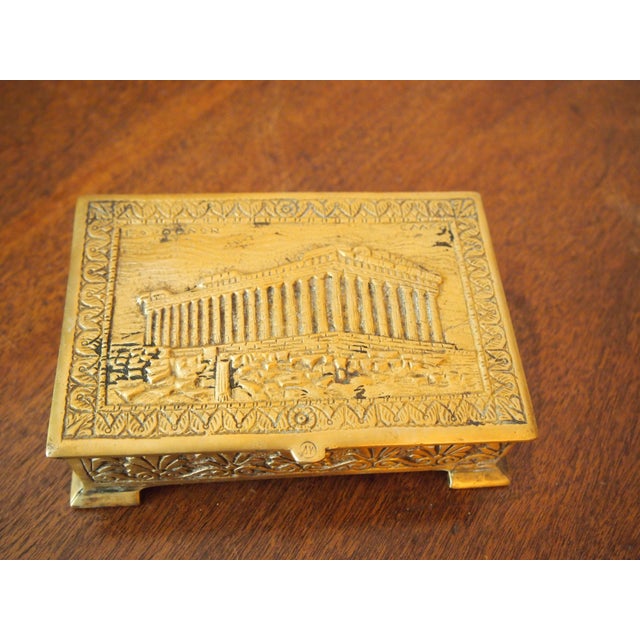 Cast brass wood-lined trinket box. Image on lid depicts the Parthenon and includes the word ΠΑΡΘΕΝΟΝ in the upper right...