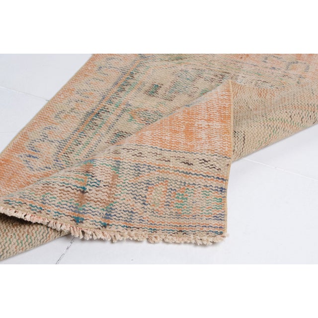 This is a vintage Turkish Oushak rug from the Mid 20th Century. The piece was hand-knotted.