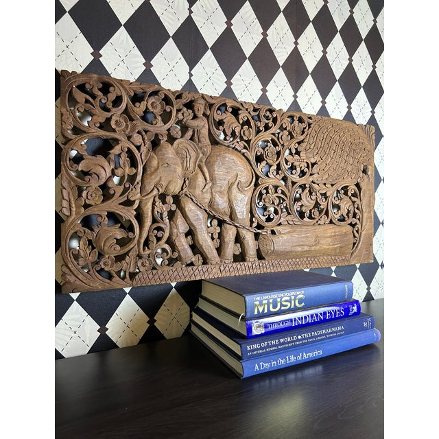 Large hand-carved teak wall panel from Thailand featuring an elephant and rider surrounded by elaborate floral and...