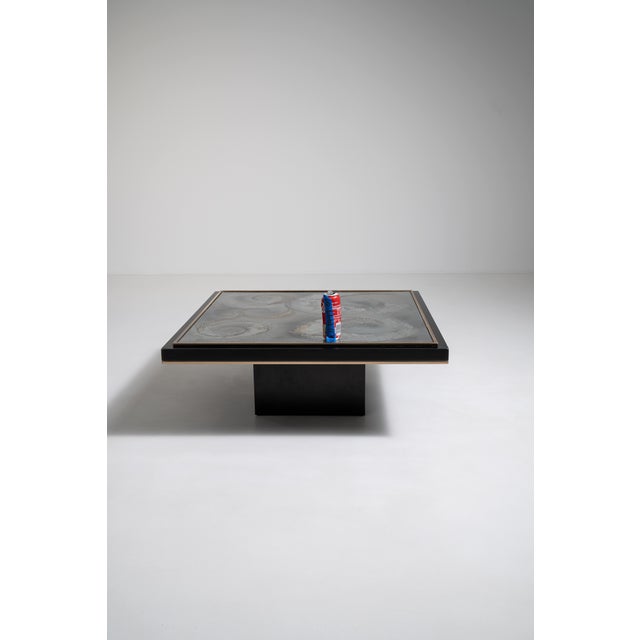 An artistic coffee table featuring eglomisé glass, a technique involving reverse-painted glass for decorative effect. The...