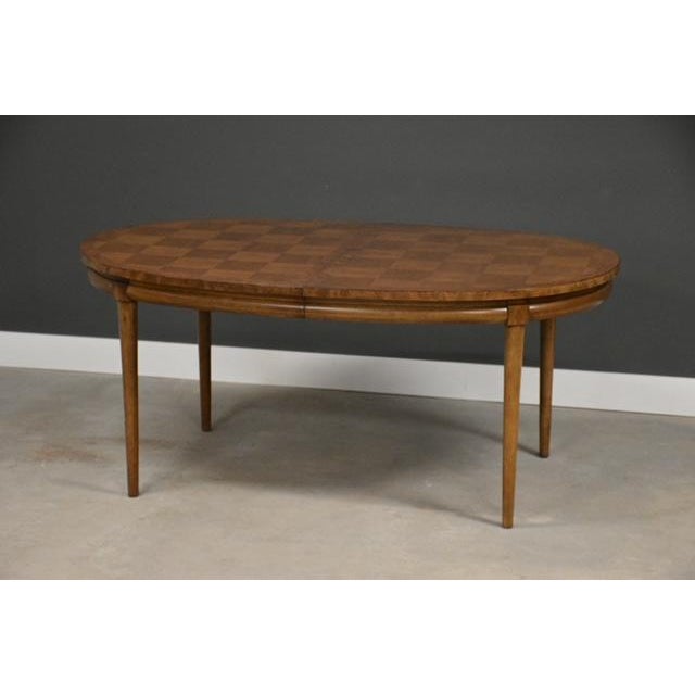 A mid century modern walnut oval dining table with two 18” leaves that fully expand the table to 104” by Thomasville...