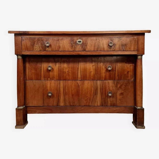Empire period commode in walnut and gilt bronze, circa 1810-1820. Front opening with three drawers. Wooden top. Essential...