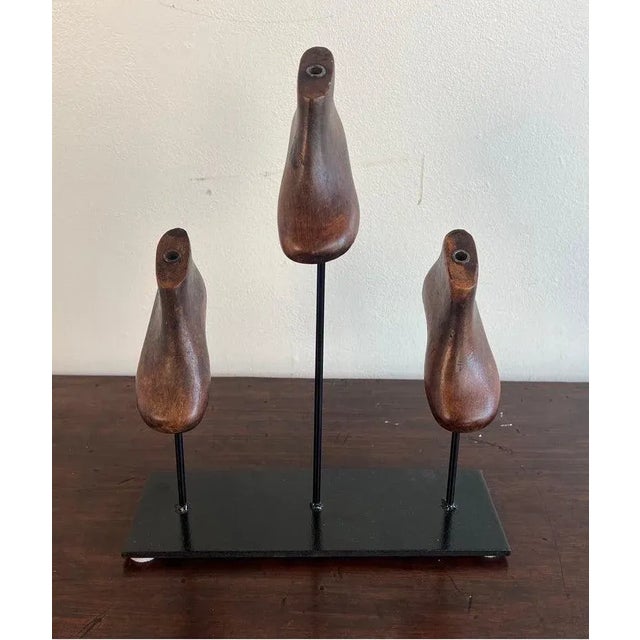 Set of three wooden child size shoe forms mounted on an iron base.