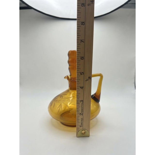 Charming vintage honey amber glass cruet featuring a bulbous body adorned with delicate wheel-cut etched floral and...