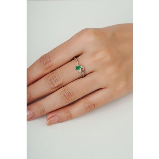Crafted in 925 sterling silver, this contemporary ring features a 0.55-carat natural oval emerald measuring 4 x 6 mm at...