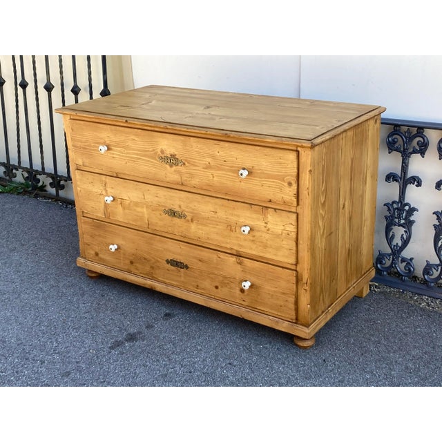 This spacious Central European three drawer chest is largely bereft of any decoration except for an ogee crown molding...