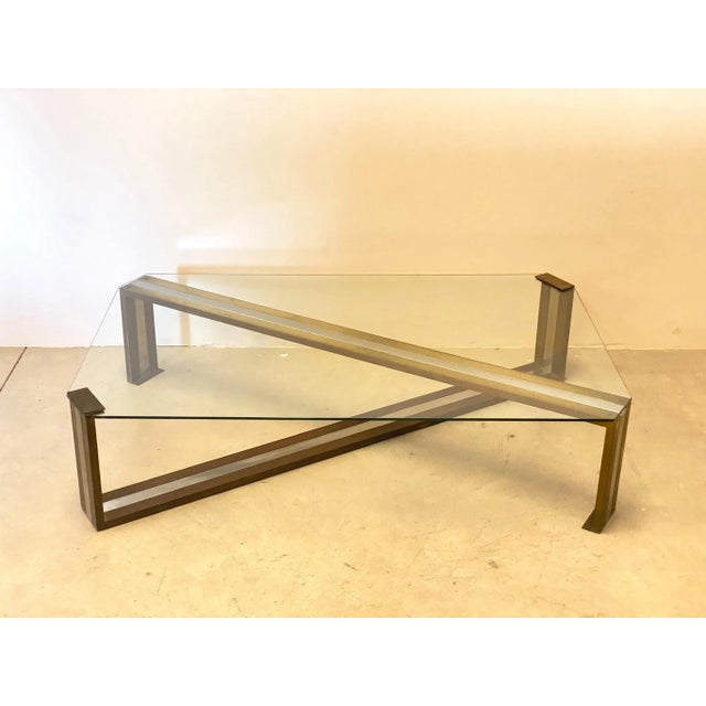 1970s coffee table, frame composed of two bands of chromed steel and brass, glass top, oxidation of brass is present and...