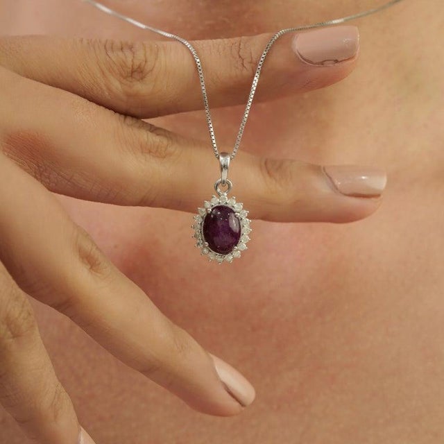 This elegant pendant features a 7.71 carat oval star ruby surrounded by 0.37 carats of round diamonds, handcrafted in 925...