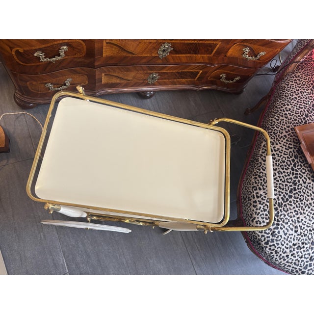 Vintage bar cart, 1960s Brass frame and two glass shelves. The elegant design with large spoked wheels, white details, and...