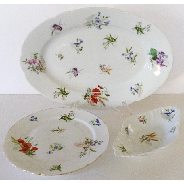 Set includes a large platter, vegetable side dish and a raised cake plate each decorated with scattered spring flowers....
