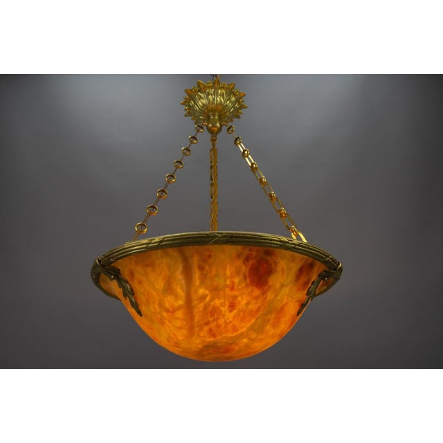 A magnificent Neoclassical style amber color alabaster pendant ceiling light fixture with an ornate bronze frame. France,...