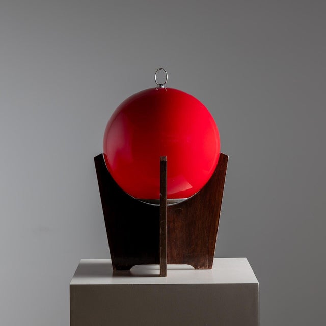 Table lamp on a veneered tripod base with a red spherical lampshade with nickel-plated ring. Attributed to Luciano...