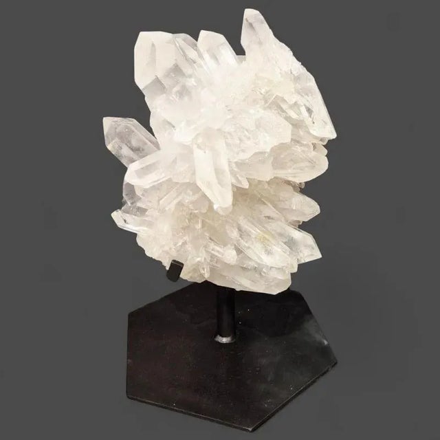 A striking and monumental crystal rock cluster sourced from Brazil, mounted on a custom black metal and stone base.This...