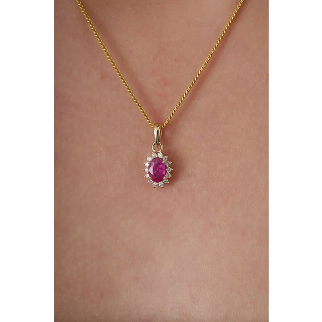 This pendant showcases a 0.7 carat ruby set in 14k yellow gold. The ruby measuring 4.2 x 6.2 mm, secured in a classic...