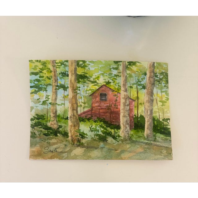A charming woodland scene featuring a rustic red structure tucked among tall sunlit trees. Fresh greens and layered...