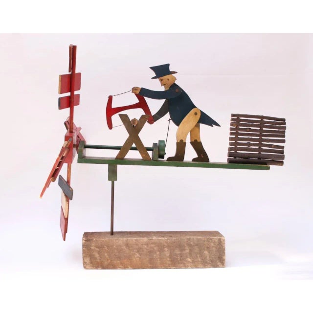 Charming whirligig depicting a figure resembling Uncle Sam sawing a log mounted to a wooden base. Hand carved, painted,...